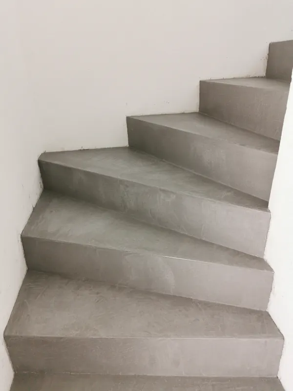 Gewendelte Treppe mit fugenloser grauer Oberfläche